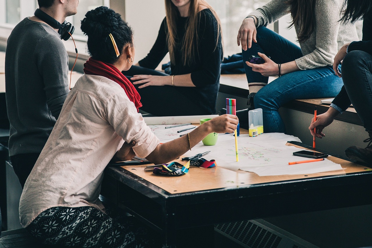 5 Personen sitzen am Tisch und besprechen etwas